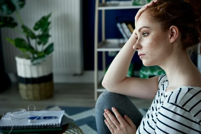 Pensive young woman touching her head, reflecting on stress like in worst MIL stories.