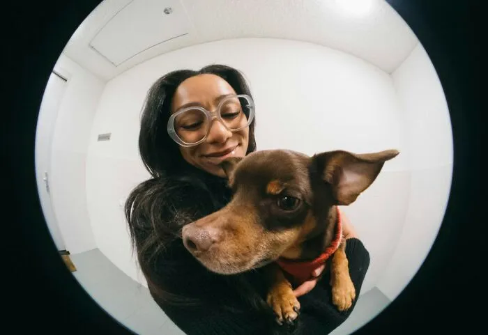 Fisheye view of a woman holding her small brown dog during a story about pet care.