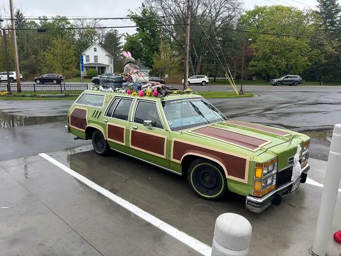 Classic green station wagon with wood paneling parked outdoors featuring nostalgic photos of 80s cars