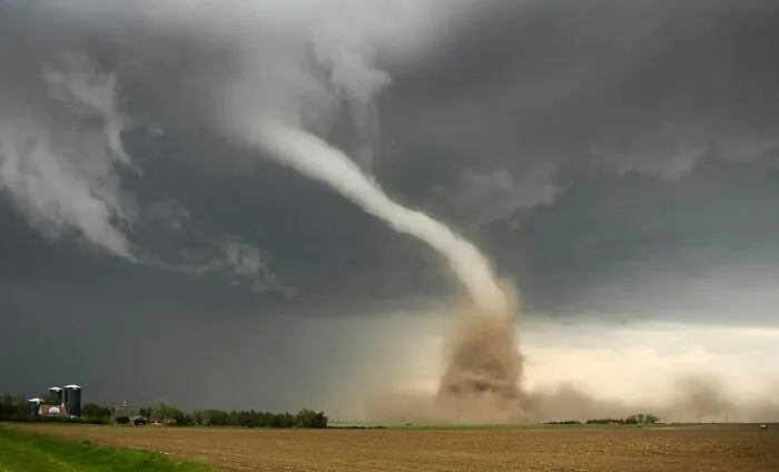 A massive tornado touching down in a field, giving people an urgent feeling to leave immediately