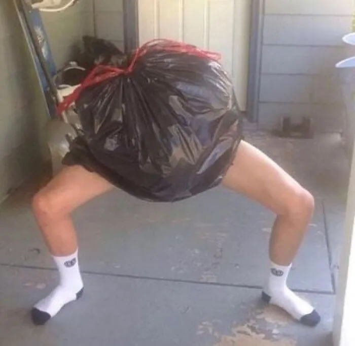 Person wearing large black trash bag bending over in distorted pose