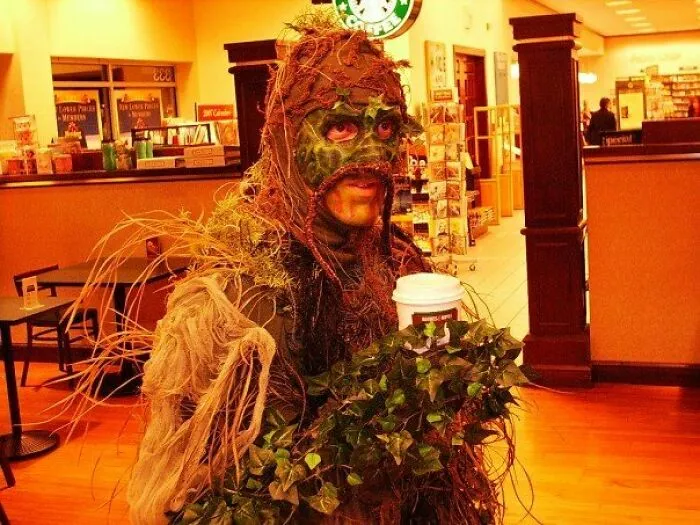 Person in a swamp monster disguise holding a coffee cup as a creative Halloween costume idea