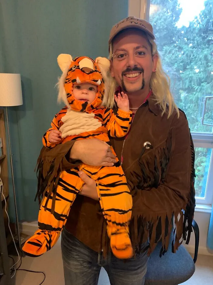 A man dressed as Joe Exotic holding a baby in a tiger suit, serving as creative Halloween costume ideas.