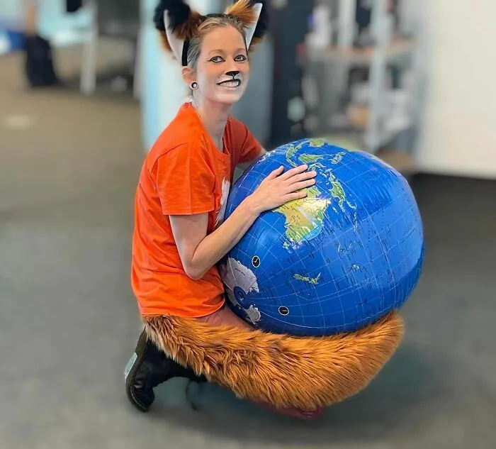 A woman dressed up as the Firefox browser logo holding a globe for creative Halloween costume ideas.