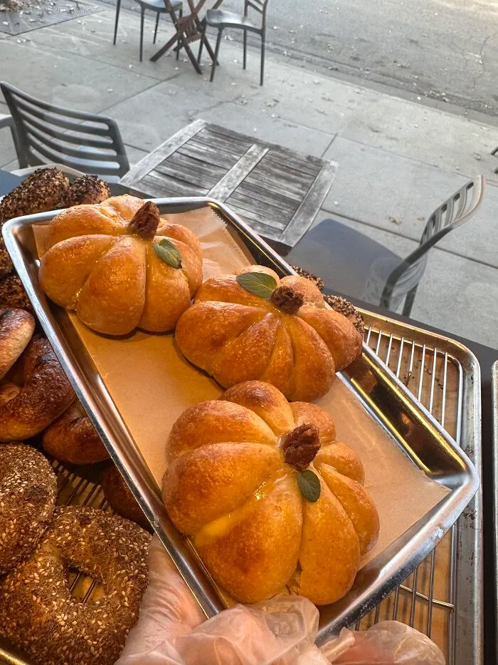 Tray of golden-baked pumpkin-shaped rolls, a creative option for Halloween foods.