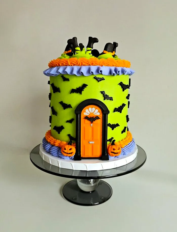 A bright green cake featuring a spooky orange house door and bats, showcasing unique Halloween foods.