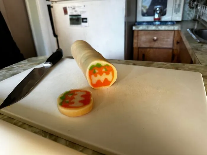 A slice of pumpkin roll cookie dough on a cutting board representing fun Halloween foods ideas.