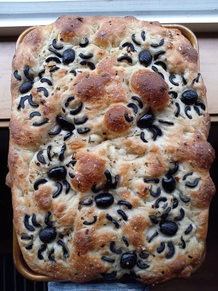 Freshly baked focaccia bread designed as Halloween foods featuring black olive spiders