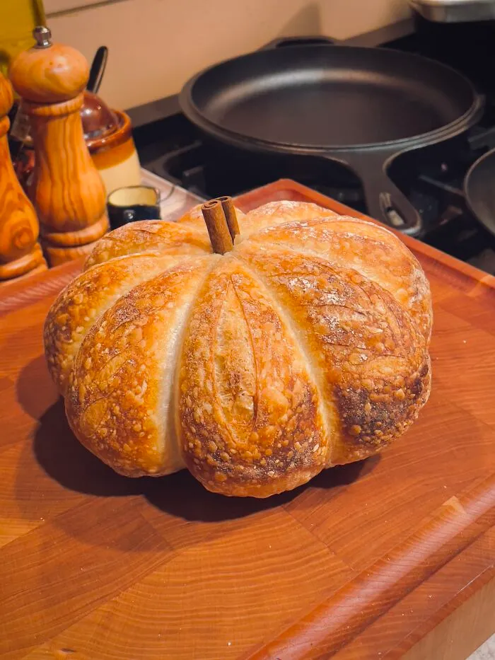 Freshly baked sourdough bread shaped like a pumpkin, a cozy idea for Halloween foods.
