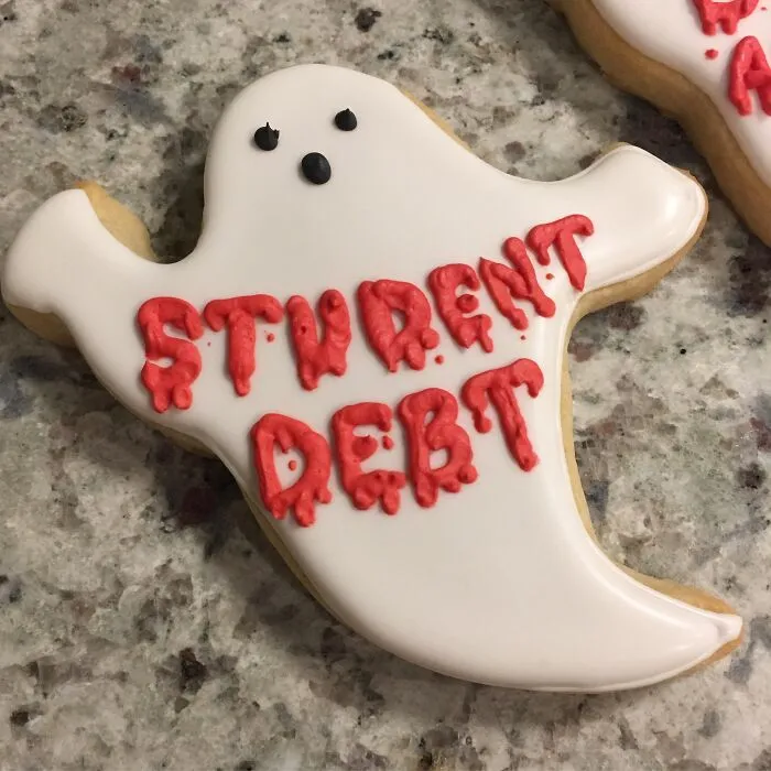 Ghost-shaped sugar cookie with Student Debt written in red icing, perfect for funny Halloween foods.