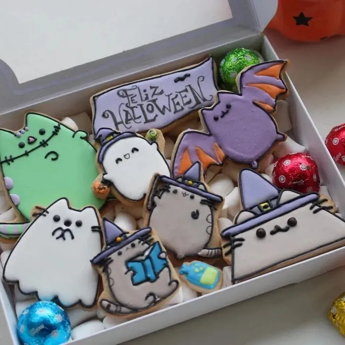 Box of adorable cat-themed Halloween foods cookies decorated as ghosts, bats, and witches.