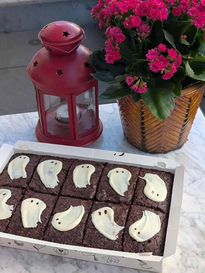 Box of chocolate brownies with white icing ghosts as delicious Halloween foods.