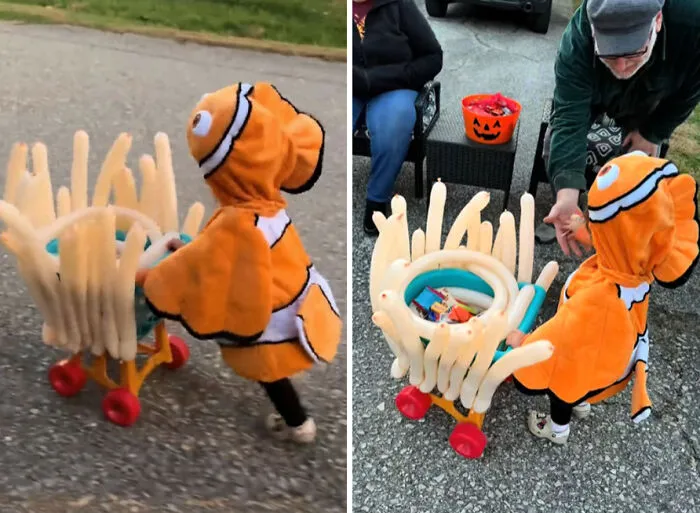 A toddler wearing a Nemo clownfish Halloween costume pushing a cart covered in balloon sea anemones