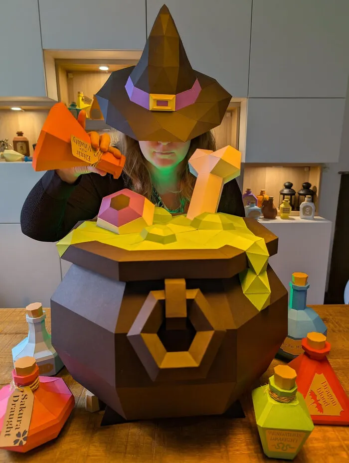 Person in a witch hat making a papercraft potion in a cauldron for Halloween decor