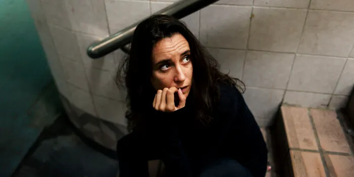 Worried woman sitting on stairs in a tense haunted house setting
