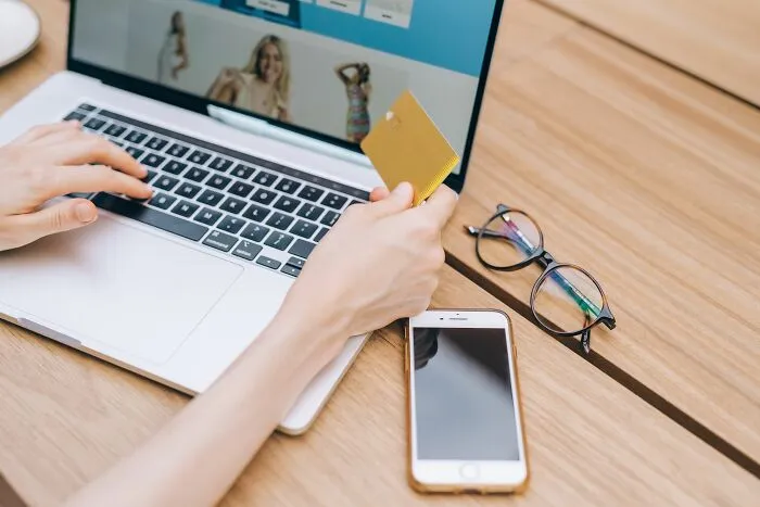 A person using a laptop and credit card for online shopping as part of practical money-saving tricks