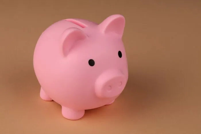A pink piggy bank representing effective money-saving tricks on a plain brown background