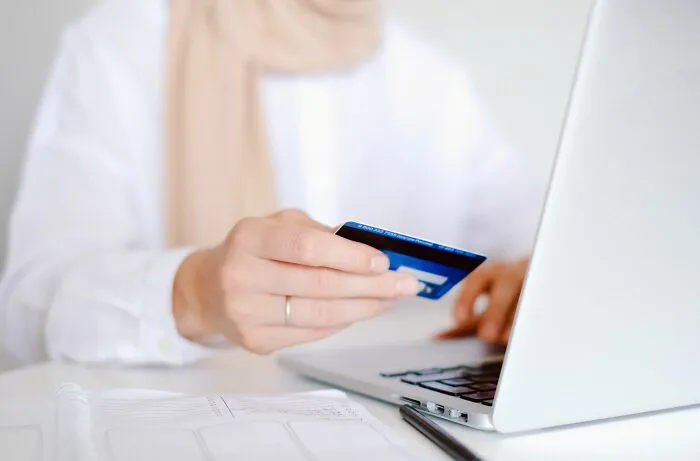 A person using a credit card and laptop for smart online shopping and money-saving tricks.