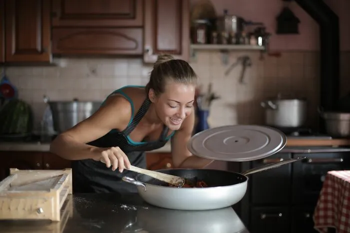 Woman cooking a home-cooked meal in the kitchen as a simple money-saving trick