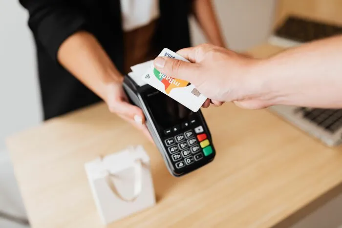 Customer tapping a credit card on a terminal, an easy money-saving trick for daily purchases