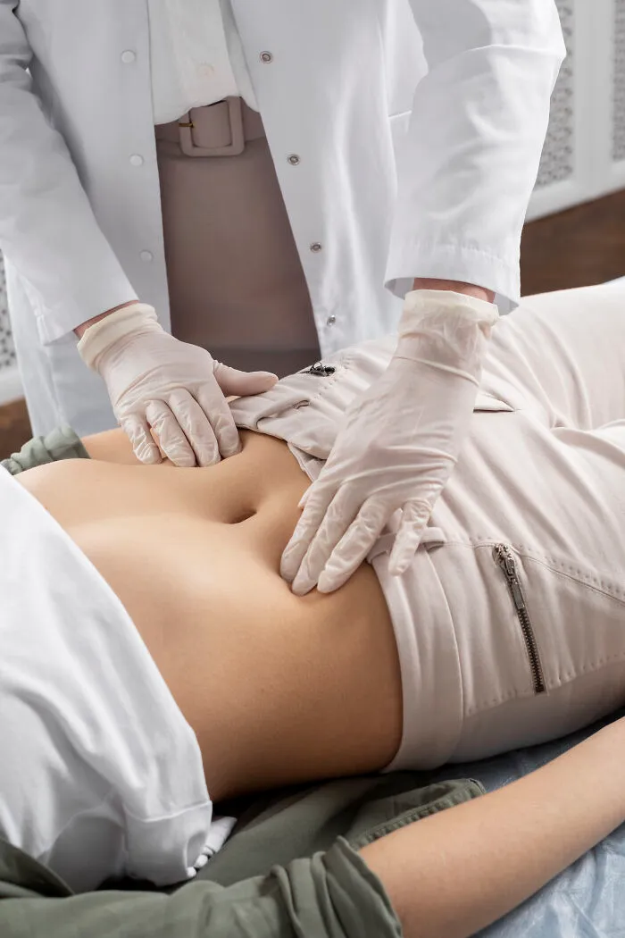 A doctor wearing gloves performing an abdominal exam on a patient to address health problems in Gen Z.