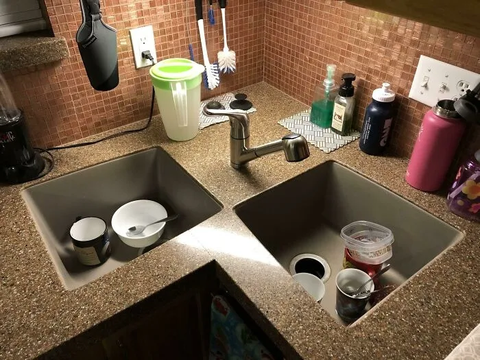 A poorly aligned corner kitchen sink with dirty dishes, a home renovation design fail