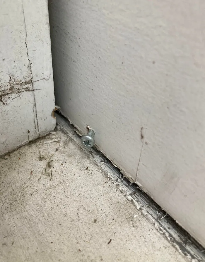 A screw placed poorly in a corner baseboard during a rushed home renovation project