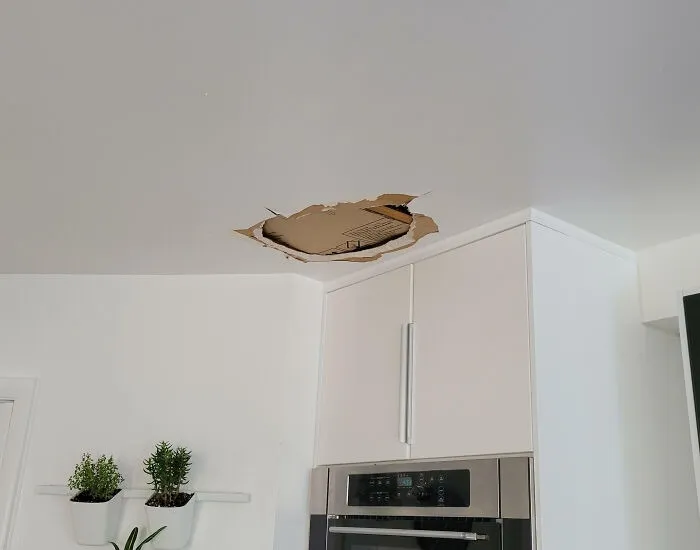 A kitchen ceiling with a large hole, demonstrating a home improvement and renovation fiasco.