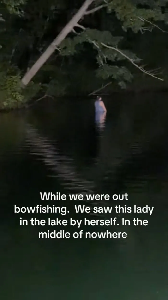 A mysterious figure standing in dark lake water at night, featured in creepy photos.