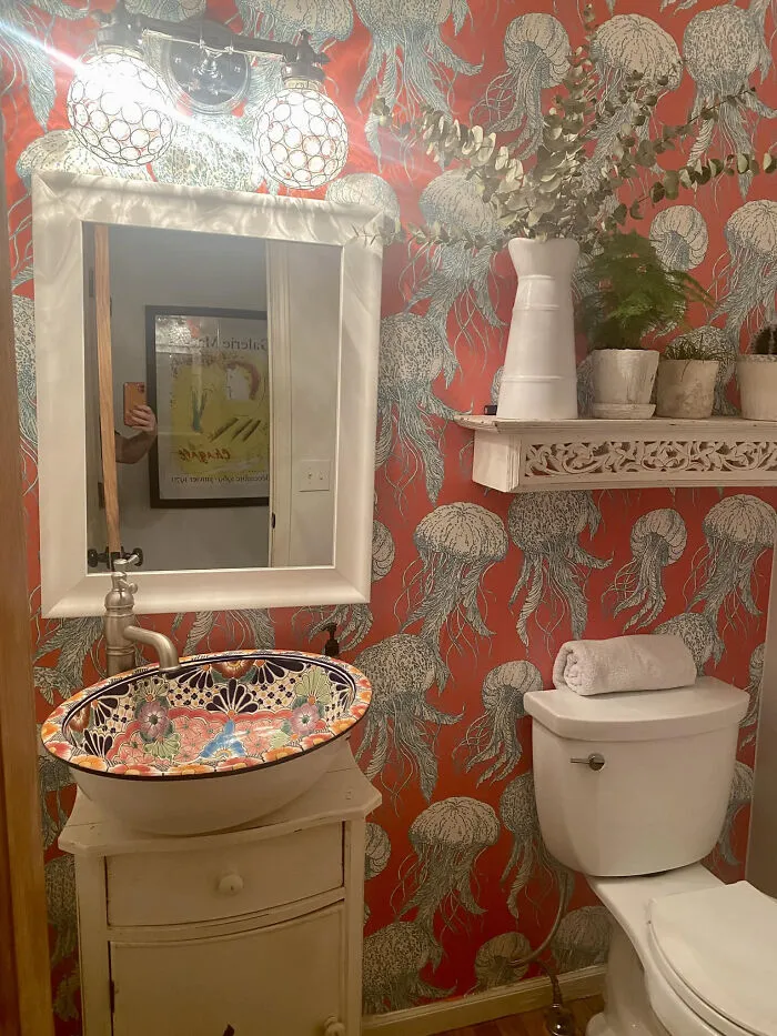 Vibrant bathroom home makeover with orange jellyfish wallpaper, patterned sink, and potted plants.