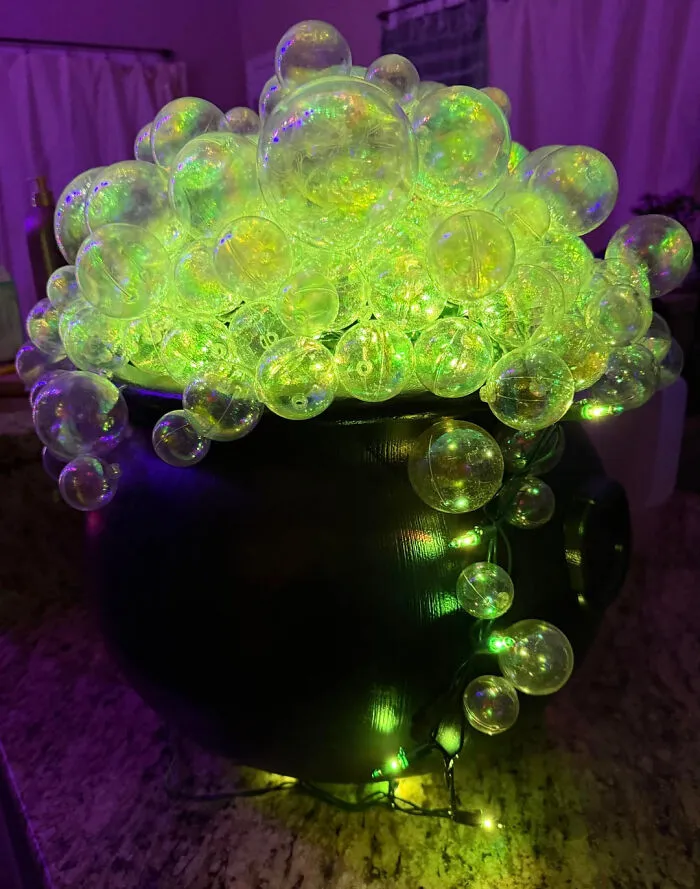 Glowing cauldron bubbling with green light orbs making a spooky Halloween display at home