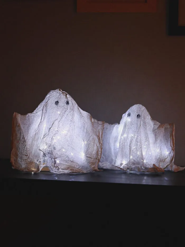 Two glowing illuminated ghost figures inside homes for Halloween decorations.