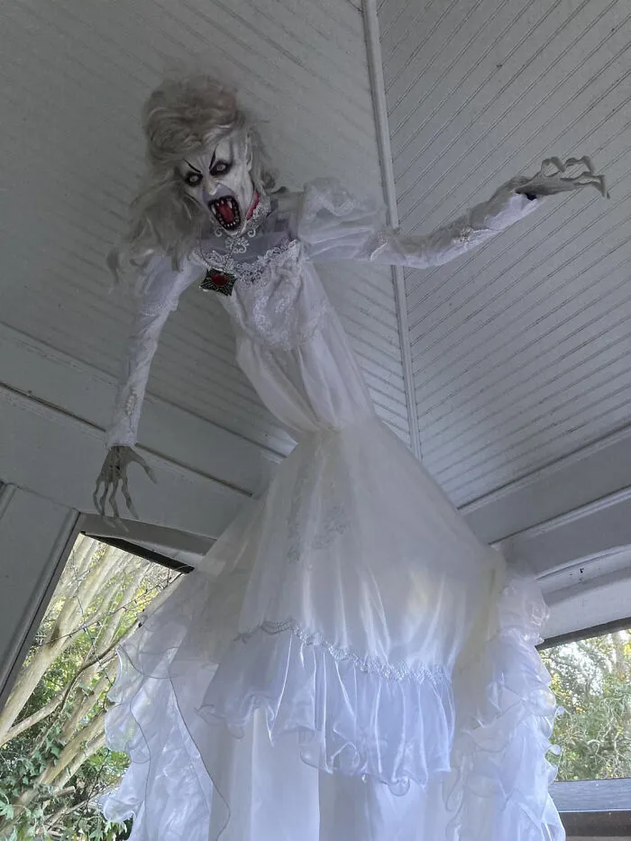 Spooky ghost bride decor hanging from a porch for Halloween.