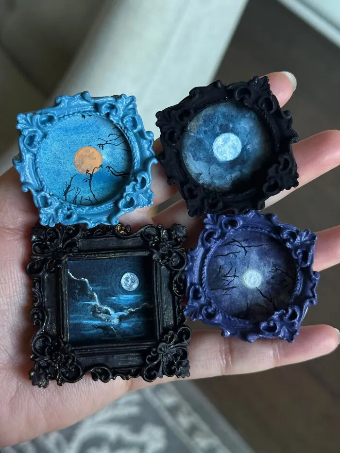 Hand holding tiny hand-painted spooky full moon pictures in ornate frames for Halloween decor