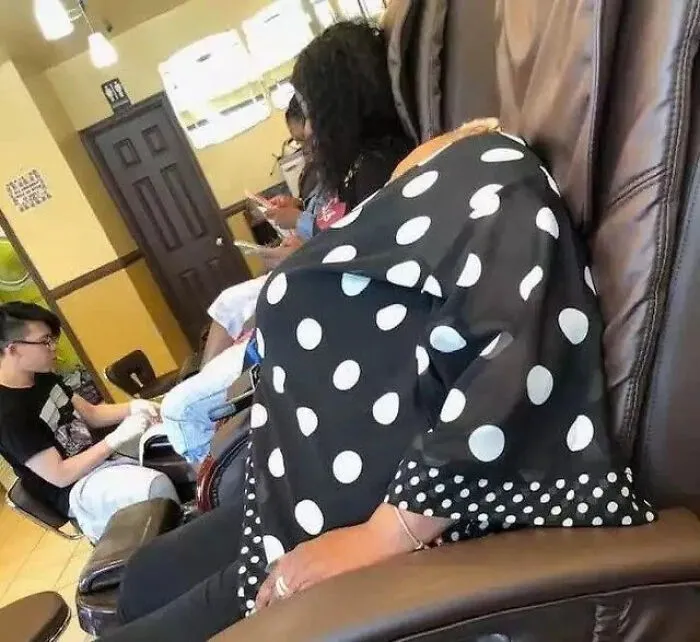 A woman in a polka dot shirt leaning back in a salon chair creating a perfectly confusing headless illusion.