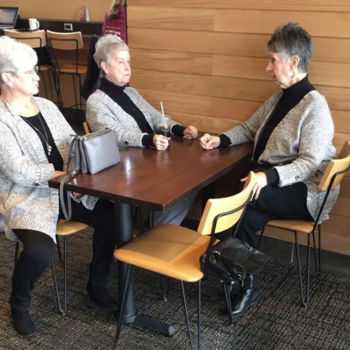 Three elderly women with identical outfits sitting at table glitch