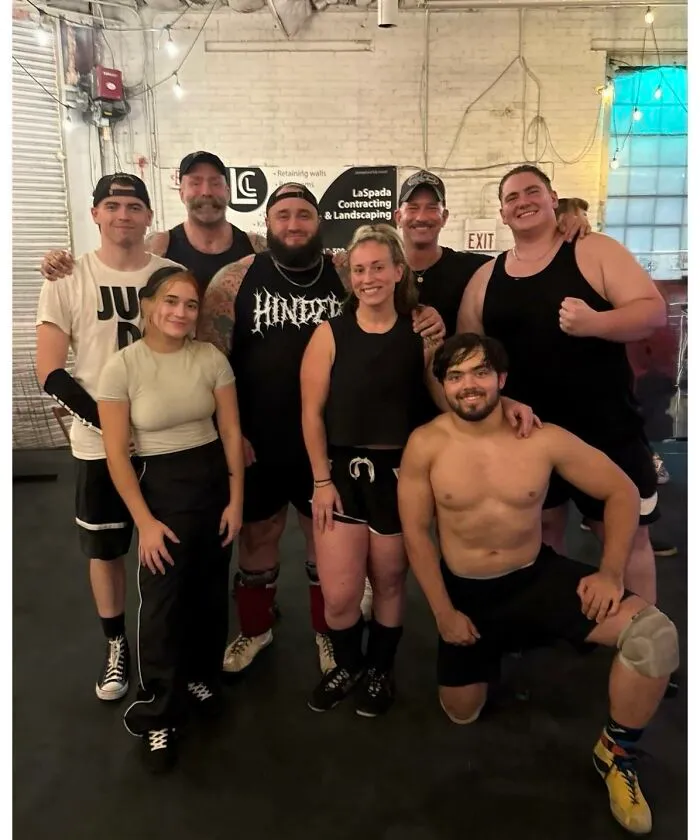 Group of friends and athletes posing together in a gym captured in photo for the last time