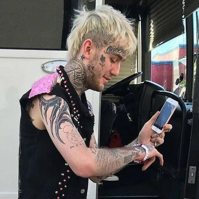 Lil Peep looking at his smartphone near a vehicle, captured in photo for the last time in his life