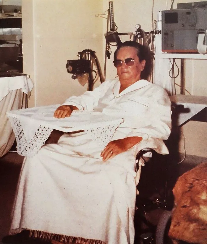 An elderly woman wearing sunglasses sitting in a wheelchair, one of the people captured in photos for the last time.