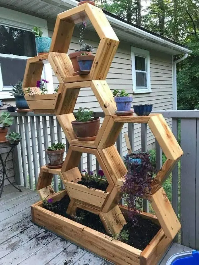A multi-tiered vertical planter crafted from wooden creations in a honeycomb pattern on a deck.