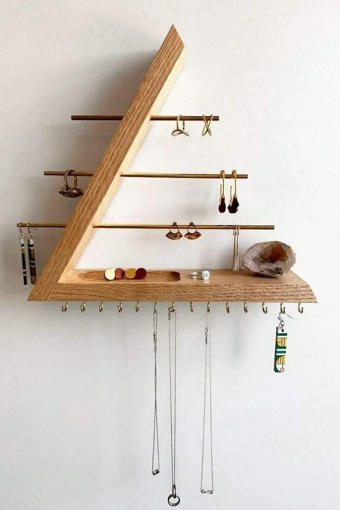 Triangular wooden jewelry organizer on a wall, depicting clever wooden creations