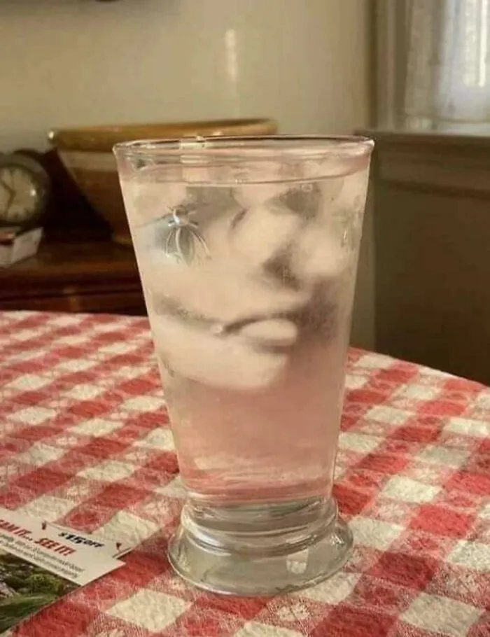 Ice cubes in a glass of water forming a face, playing tricks on your eyes.