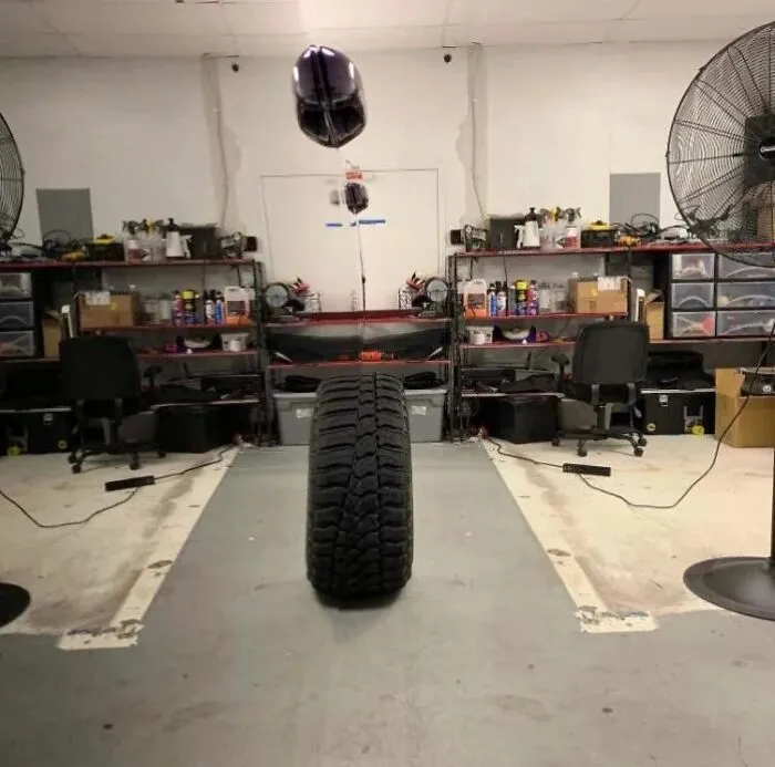 A tire sitting in a shop creating a photos playing tricks on your eyes illusion with a purple balloon above it.