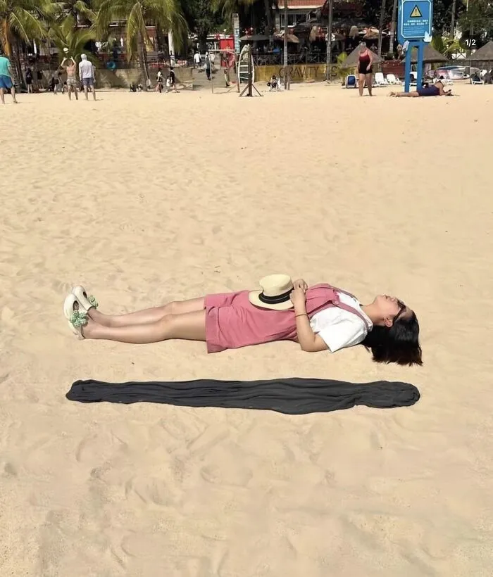 A woman lying on the sand creates a shadow optical illusion, part of photos that play tricks on your eyes.