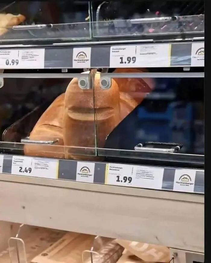 A funny photo of bread loaves behind display glass appearing to have a face