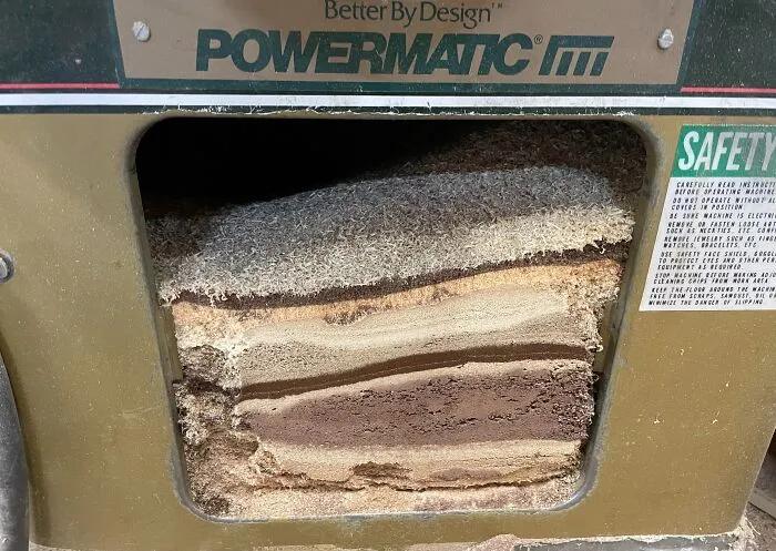 Layers of sawdust inside a woodworking machine looking like geological rock strata as eyes playing tricks.