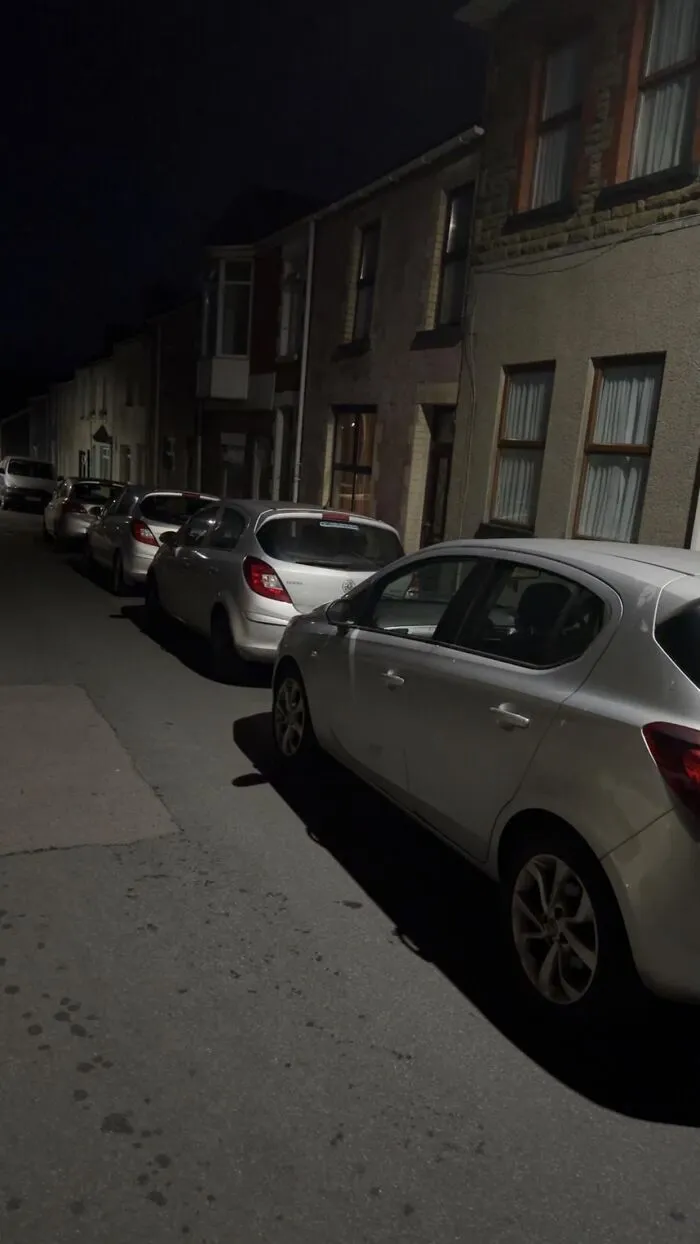 A line of identical silver cars parked at night, creating photos that make your eyes play tricks