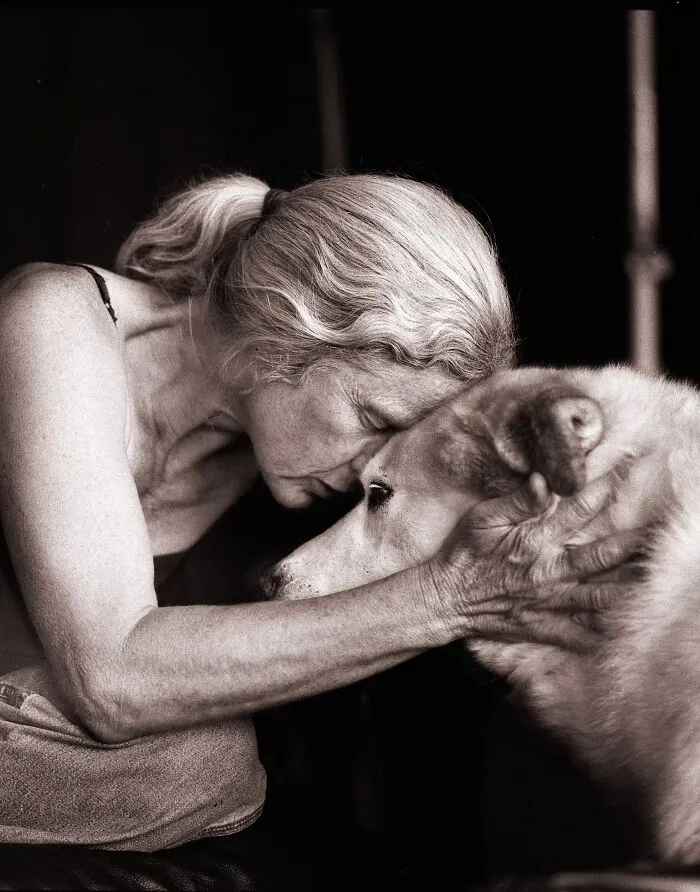 An intimate portrait photo showing a loving connection with a woman leaning her forehead against her dog