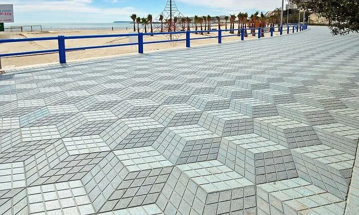 A seaside promenade in Spain decorated with a geometric 3D cube pattern pavement