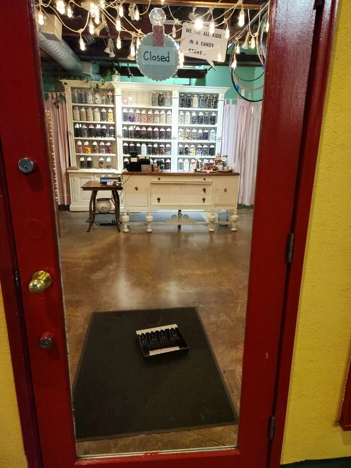 Interior view of a cozy shop seen through a glass door, showcasing useful and ingenious things inside.